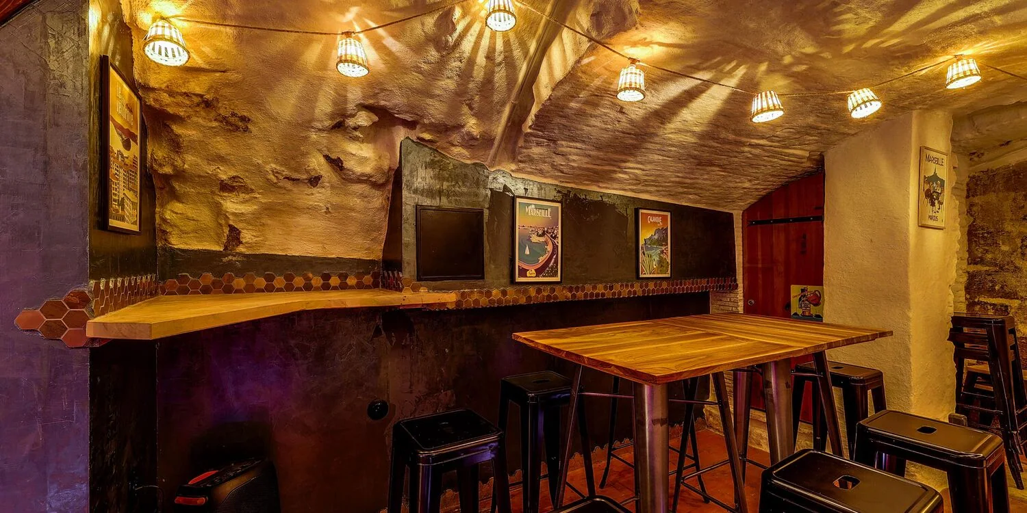 Tables hautes et murs en pierre dans la cave.